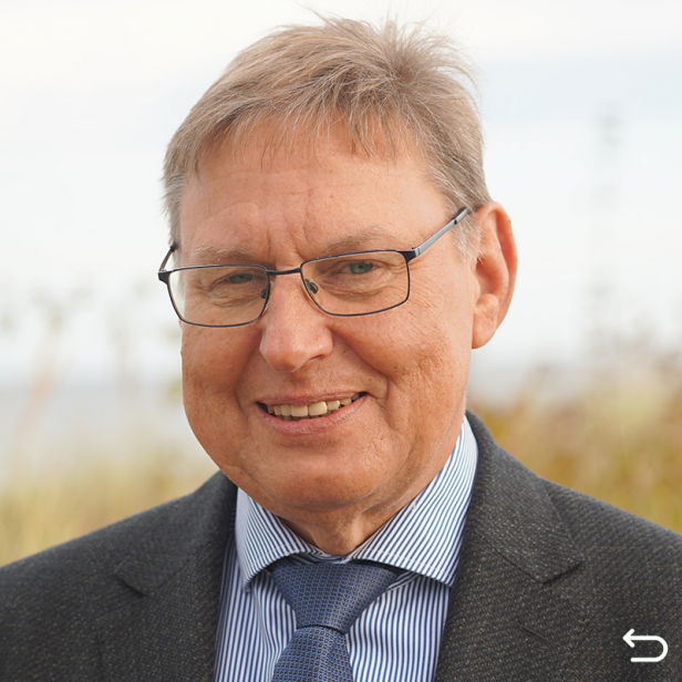 Carsten Anders im dunklen Jacket vor den Dünen in Hohwacht