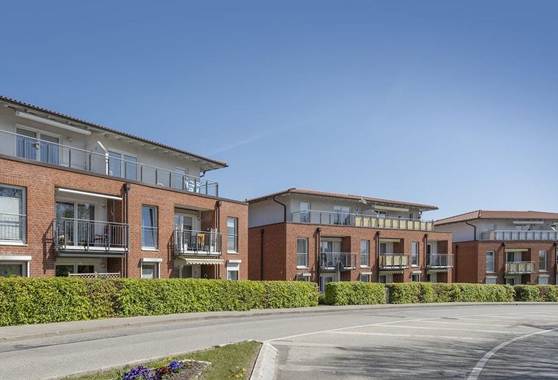 Seniorenresidenzen, drei Gebäude an einer Straße hinter grünen Hecken